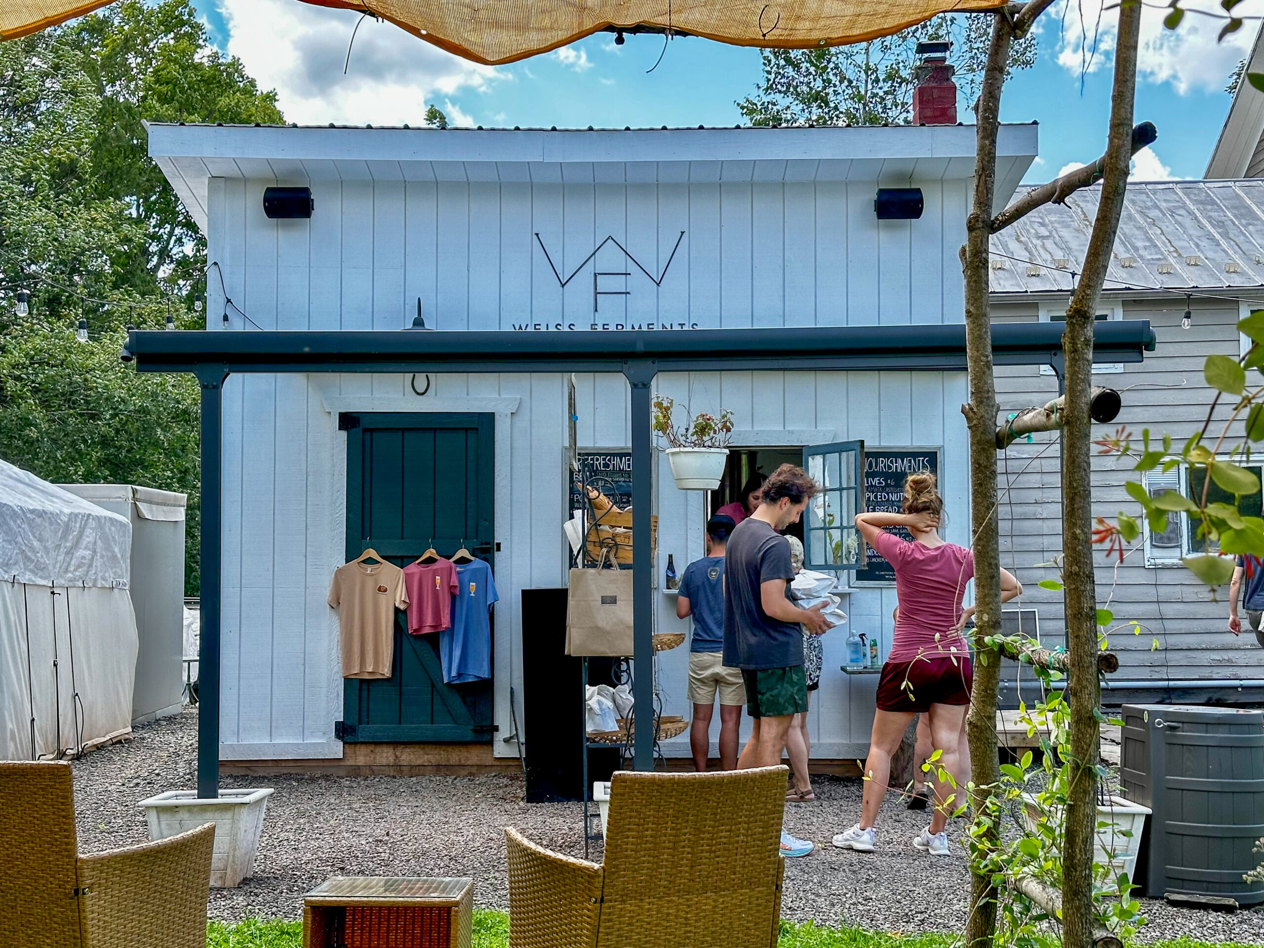 Looking at the front of the Weiss Ferments brewhouse and point of sale. People are standing in line to order and you can see some of the local furniture.