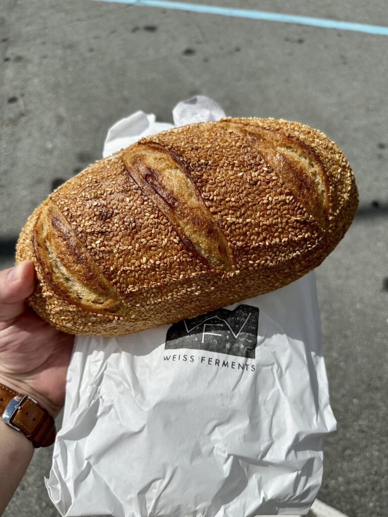 Me holding a loaf of bread covered in sesame seeds.